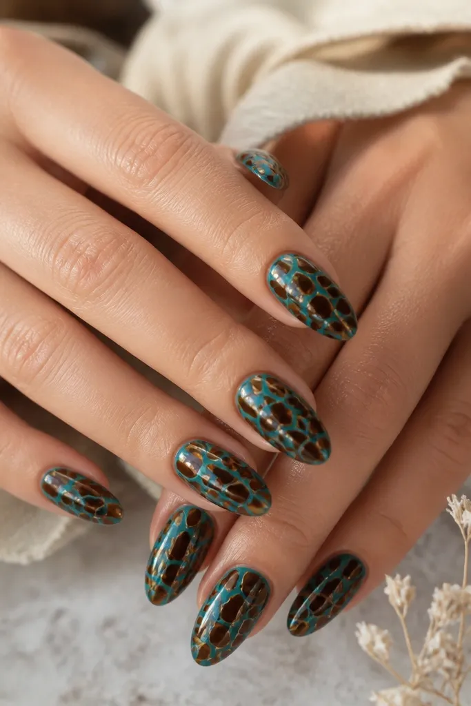 Ten glossy almond nails. The base is ocean teal, slightly lighter than turquoise. The tortoise pattern looks like a mosaic: sepia-brown irregular tiles with tiny amber gaps between them, creating a cracked-shell effect.