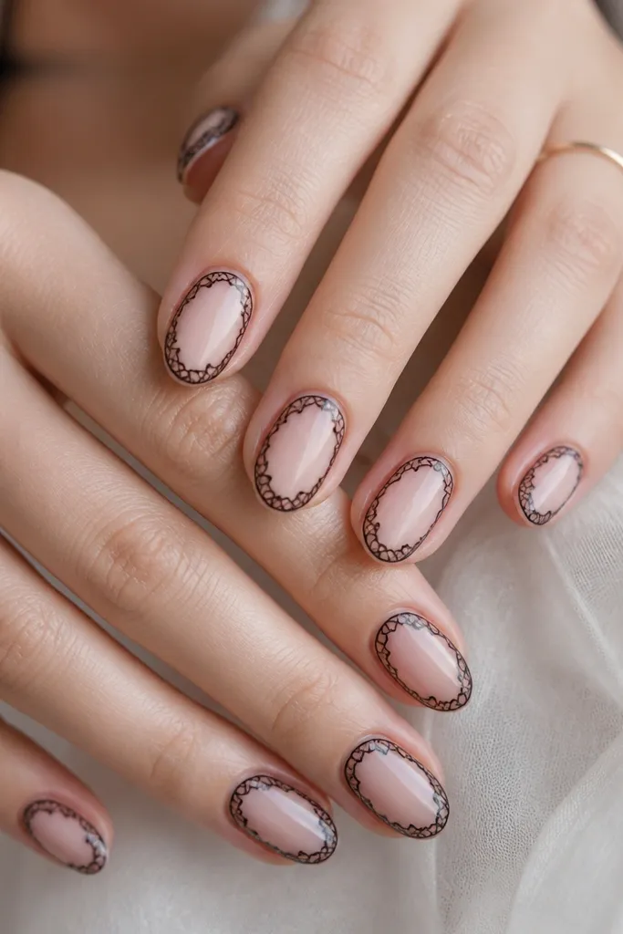 Short oval nails with a sheer pink base. On each nail, a thin black lace-like outline forms a curved border around the nail, leaving the center mostly clear. Glossy finish.