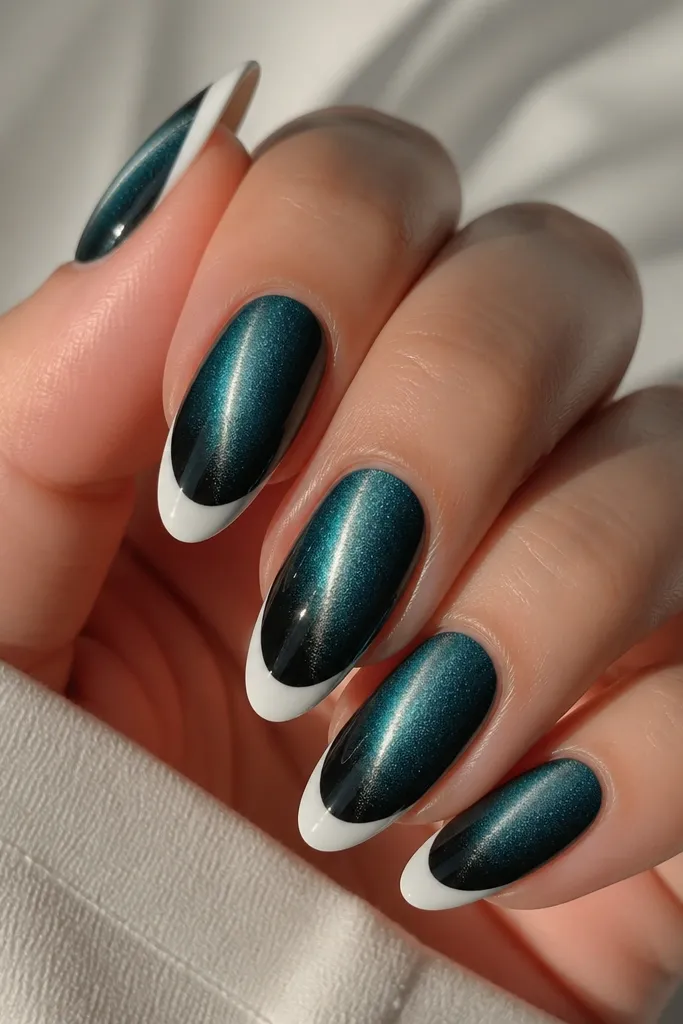 Nails show a teal cat-eye base that deepens into black toward the lower half. The shimmer stripe runs through the center. French tips are milky white and opaque enough to look bright but not chalky.