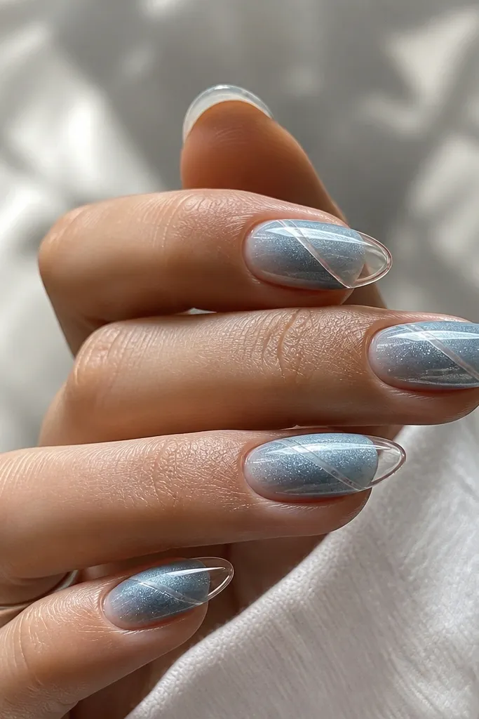 Icy blue cat-eye nails with a cool silver-blue stripe. The french tips are clear or glassy, like a transparent outline with a crisp boundary, not filled solid.