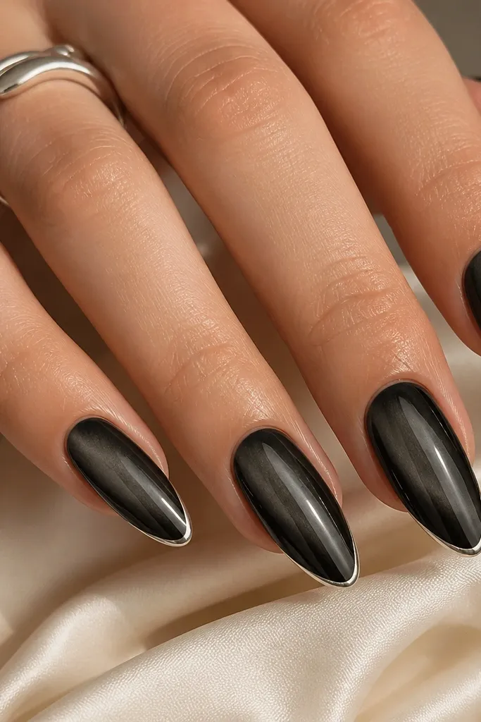 Soft black cat-eye nails with a smoky graphite stripe. The french tips are a silver outline line tracing the outer edge, with no solid fill, giving a thin metallic frame.