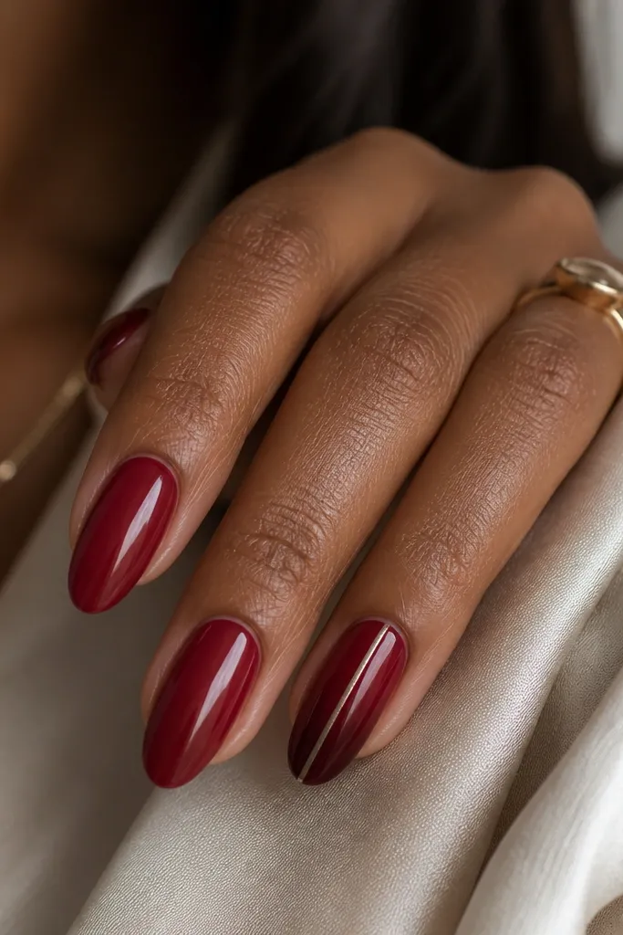 Medium almond nails in a sheer cranberry jelly on all nails. On the ring finger, there is a slightly deeper cranberry accent area near the tip, plus a single ultra-thin silver stripe running straight down the center from cuticle to tip.