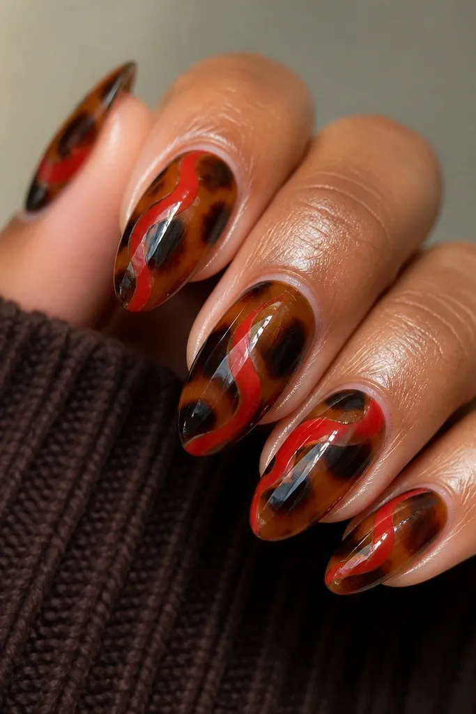 Almond nails with tortoise shell base. Thick red swirls curve from near the cuticle toward the sidewalls, layered under a glossy, slightly dimensional top coat.