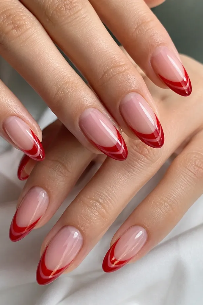 Medium-length almond nails with a clear jelly base that shows natural nail texture. The French tips are classic red and glossy. Each tip has a centered cat-eye stripe that looks like a glowing line, with a slightly darker red at the edges.