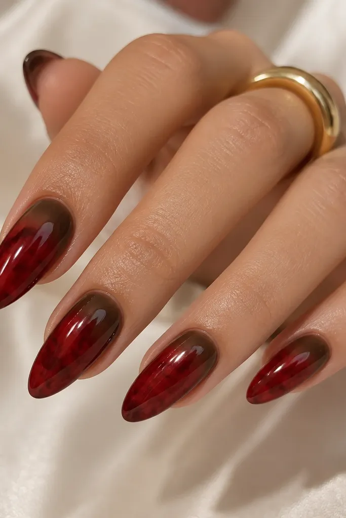 Almond nails with a cocoa-brown smoky fade at the cuticle area. The main nail is deep red, and the tortoise pattern appears as darker maroon islands that sit just below the fade, blending toward the free edge. Everything is glossy with a soft gradient look.