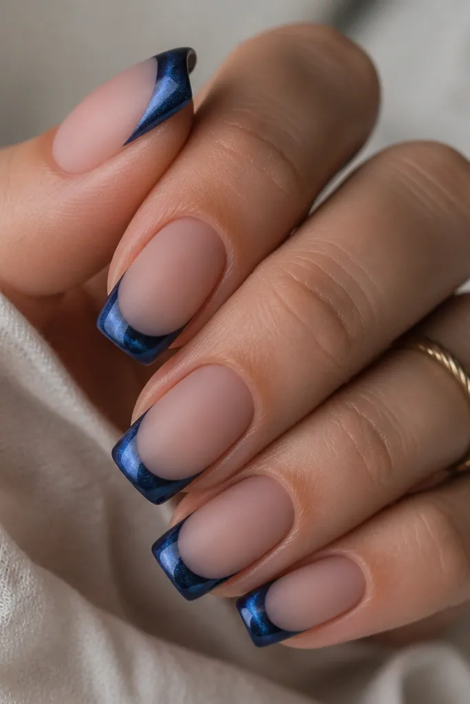 Square nails with sapphire cat-eye french tips. The tip surface looks satin-matte, but the center arc is glossy and reflective. The rest of the nail is matte nude, creating a fade effect.