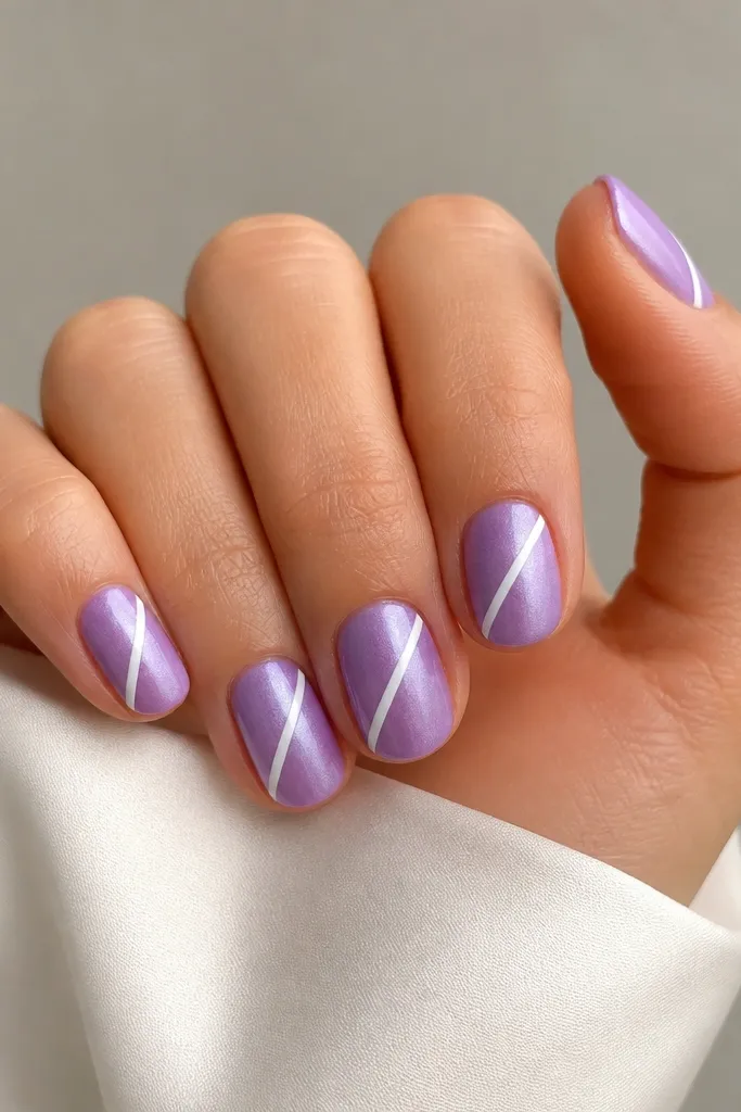 Short oval nails with a satin lavender finish (slightly pearly, not fully glossy). Each nail has a single diagonal white stripe from the lower left near the cuticle to the upper right toward the tip. The stripe is clean and straight, with crisp edges.