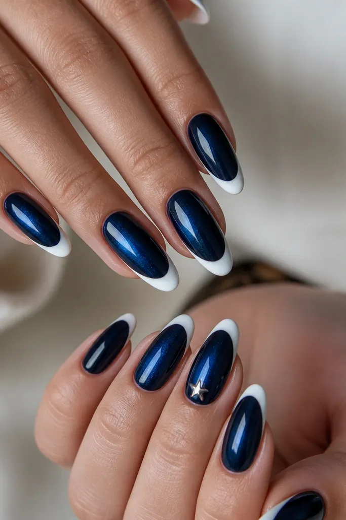 Almond nails with sapphire blue magnetic stripe centered, white French tips. One nail has a tiny five-point star dot in silver near the smile, others are plain glossy.