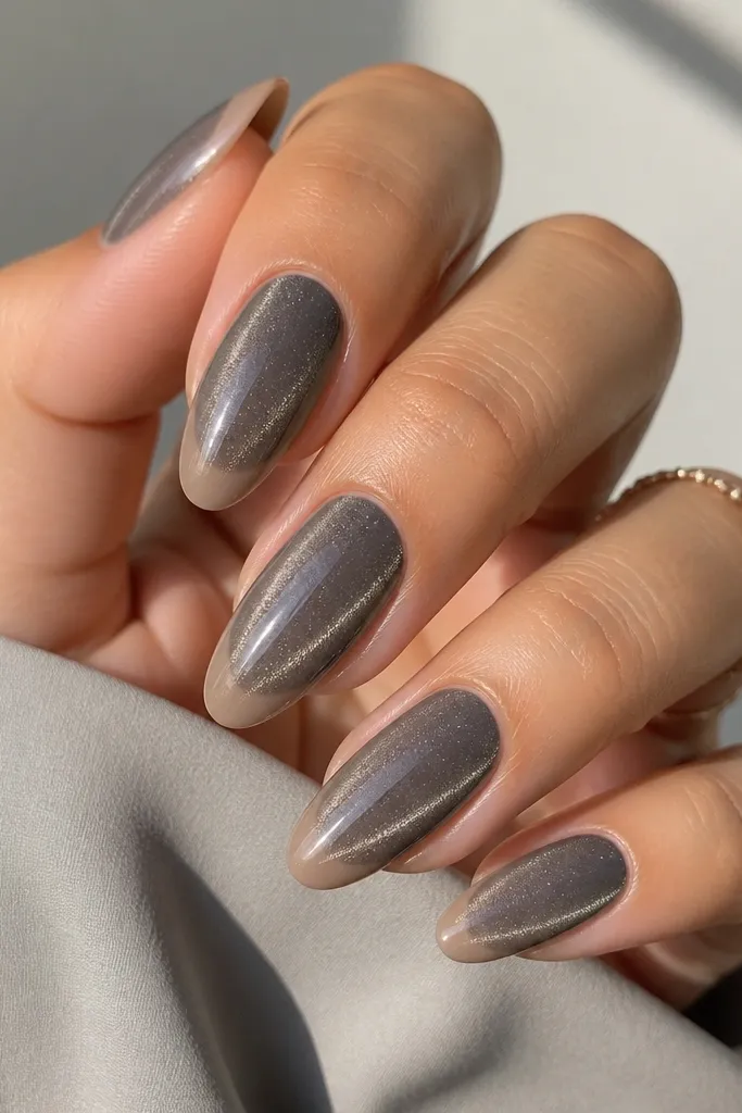Almond nails with a smoky gray magnetic cat eye base, shimmer streak visible. The French tips are not white - they're a sheer nude-beige that blends into the base, glossy and clean.