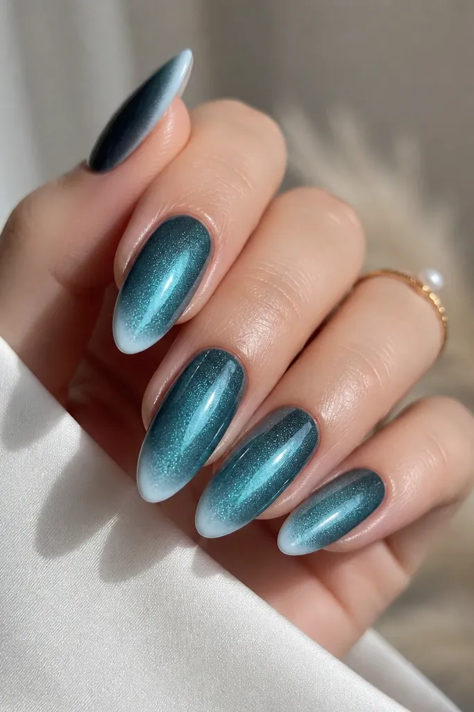 Almond nails with teal-green cat eye base. The French tip looks like a fade: white is stronger at the very edge and gradually fades into the base. Glossy finish.