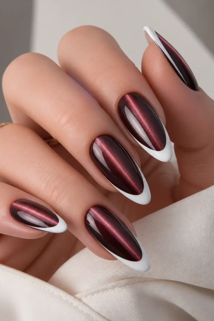 Almond nails with black cherry magnetic cat eye base and a vertical shimmer streak. The French tips are crisp white, plus a single thin black cherry side stripe running from mid-nail toward the tip on one side. Glossy top coat.