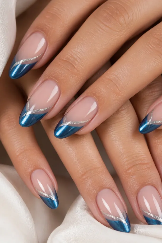 Almond nails with a sheer nude base. French tips are ocean blue cat eye with a straight center streak. On top of the tip, a thin swirl line in icy silver runs along one side of the streak.