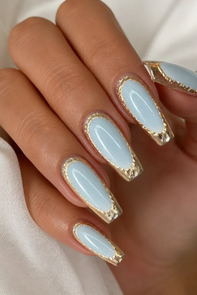 Glossy medium coffin nails with a pale blue center panel. A gold foil frame outlines the panel, and a thin white halo circle sits behind the panel center like a glowing ring.