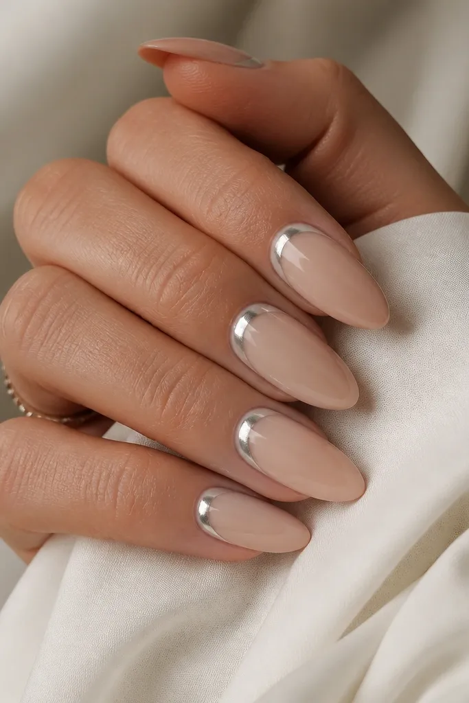 Almond nails in a nude sheer base with a silver chrome halo around the cuticle. The halo is smooth and reflective, fading slightly outward.