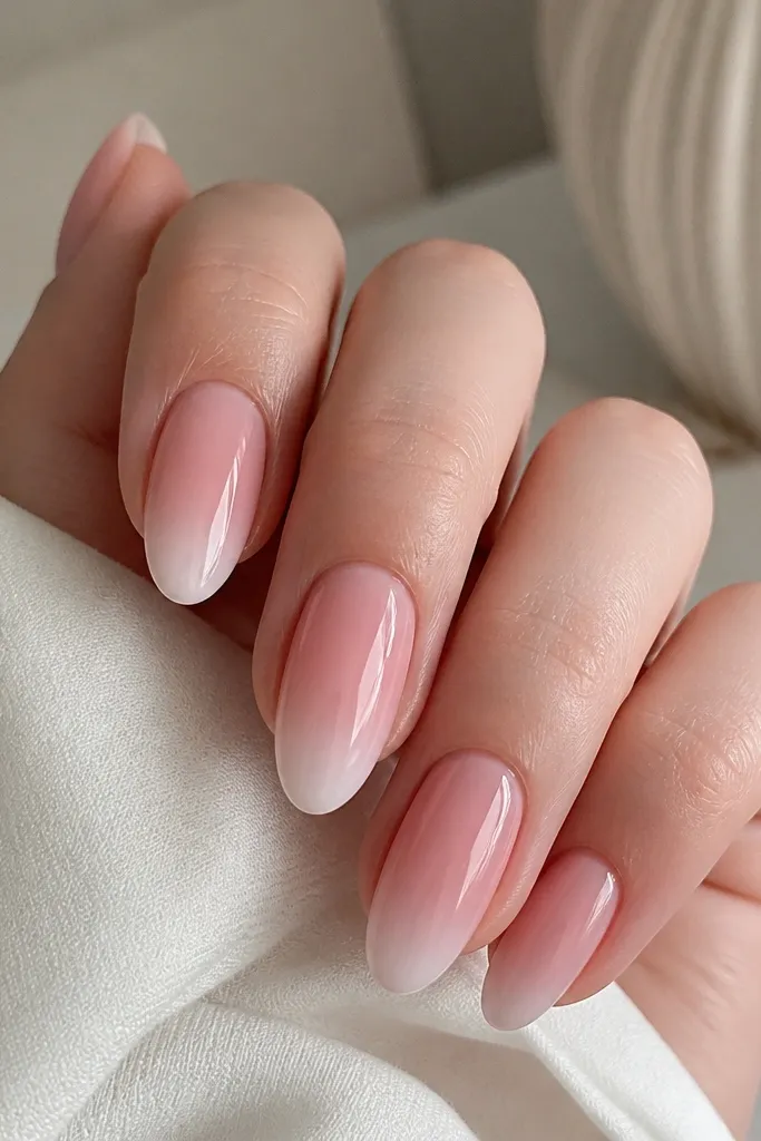 Nails show a soft ombre fade at the tips. The base is sheer rosy pink, and the tips fade from pale pink into white near the very edge, with a glossy top coat.