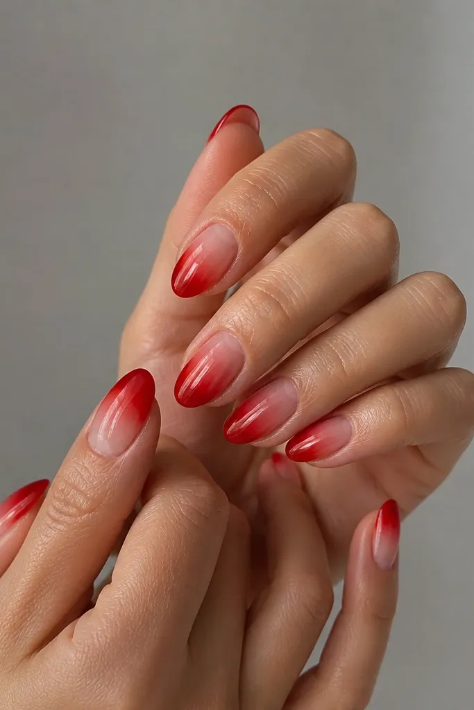 Medium almond nails with a clear center around the cuticle forming a halo; the outer area is glossy red that fades inward like an aura glow.