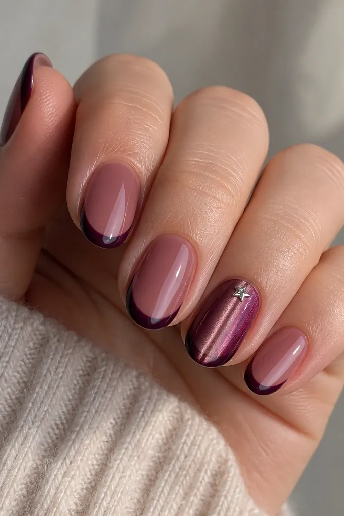 Short almond nails with a sheer berry base. French tips are deep plum, glossy and thin. Near the cuticle on one accent nail, there's a tiny five-point star in silver, and the cat eye stripe runs vertically.