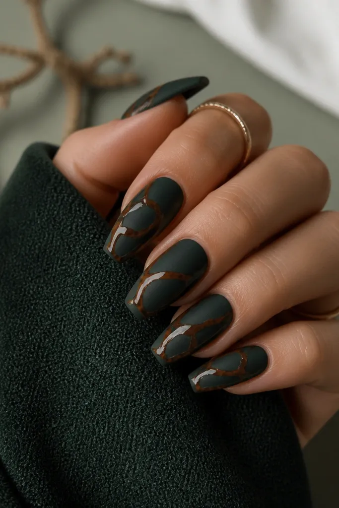 Medium coffin nails finished matte black-green. Over the matte surface, tortoiseshell lines appear in glossy caramel and dark brown, creating a shiny-on-matte contrast. The nails look velvety with sharp shell edges.
