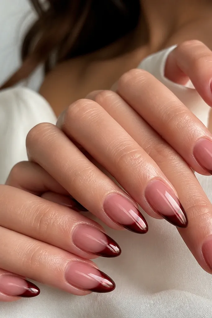 Almond nails with a sheer rose jelly base that shows nail bed glow. The french tips are burgundy red cat eye with a strong vertical stripe and a high-gloss finish.