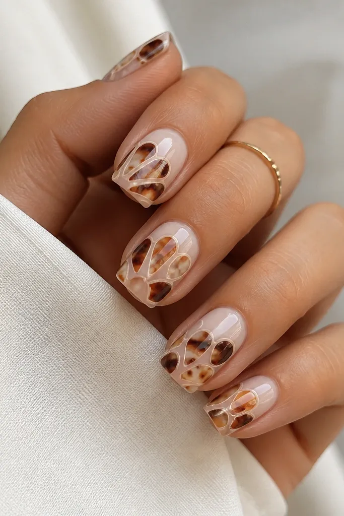 Square nails with a warm milky base. Shell pattern forms stained-glass panels with clear negative lines separating each panel. Dark brown and amber pieces sit inside each panel. Glossy.