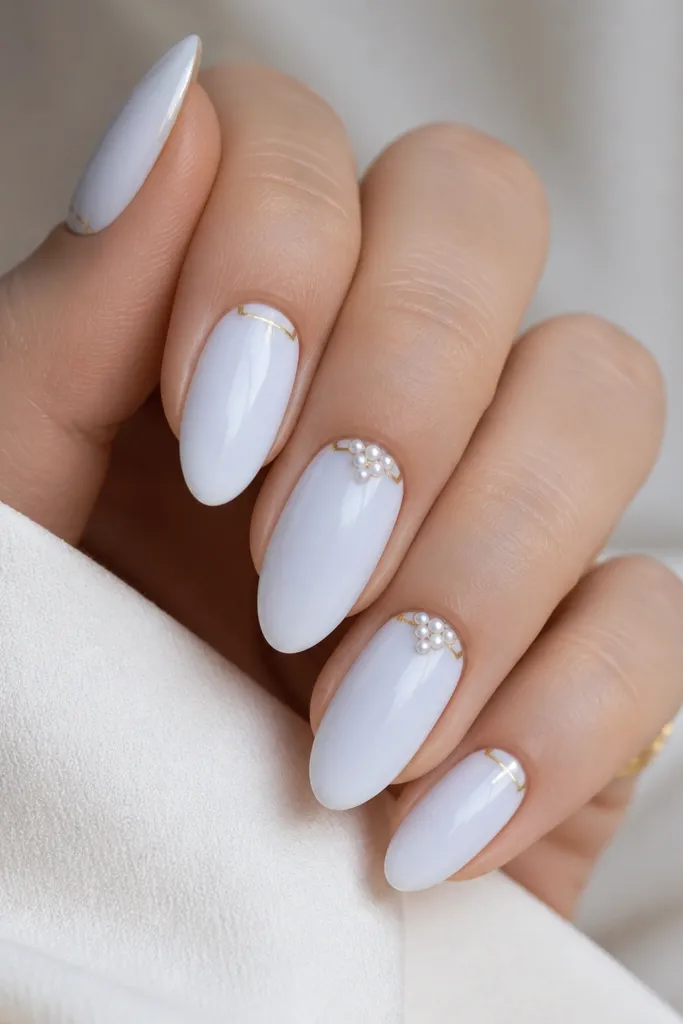 Almond nails in opaque blue-white. Near the cuticle on two nails, tiny white micro studs sit in a small cluster. Gold frame corners appear as L-shaped lines near each sidewall.