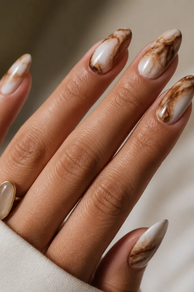 Medium almond nails with a white marbled base. Brown tortoise pieces are blended like smoke trails, not sharp fragments. Nails are glossy and have a smooth, fluid look.