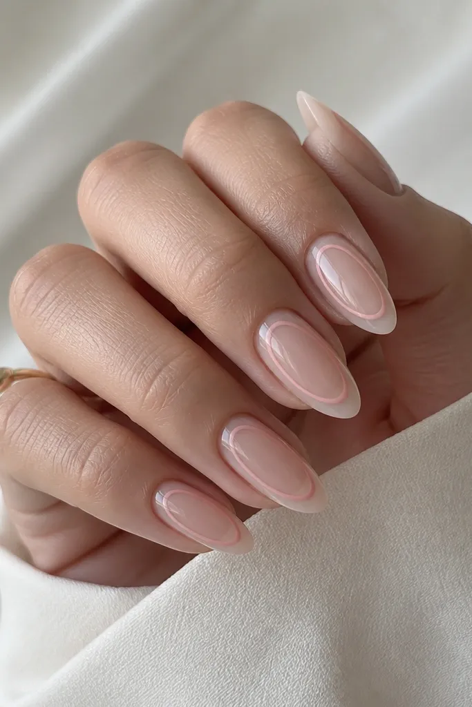 Almond nails with a sheer nude-pink base. There is a thin rose-pink line that outlines a curved shape in the center, leaving negative space between the line and the edges. The look is airy, minimal, and glossy.