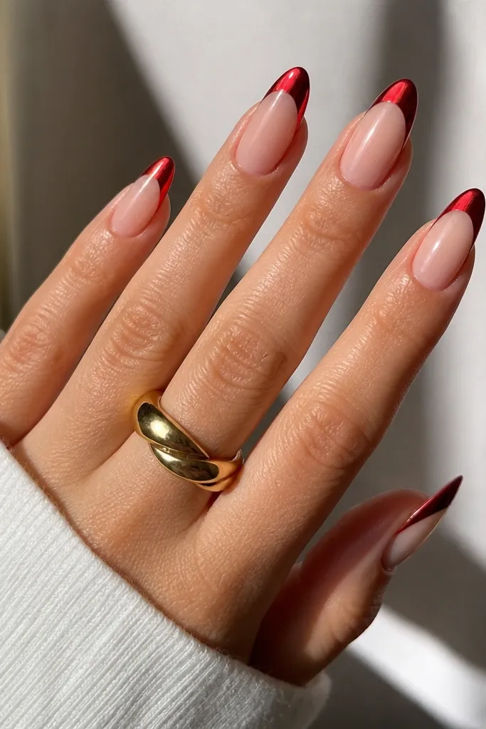 Almond nails with a sheer nude base and a french tip that's red chrome. The smile line is crisp, and the red has a metallic mirror-like shine that reflects light sharply.