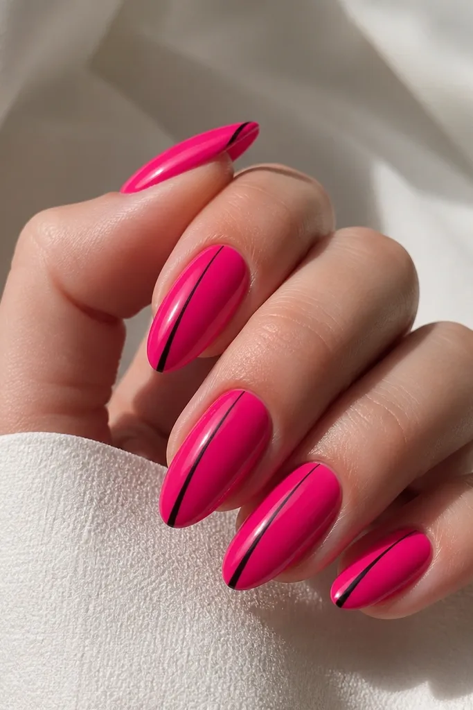 Hot pink glossy almond nails with a thin black line running diagonally from near the cuticle toward the side of the tip. The line is sharp and minimal, with clean negative space around it.