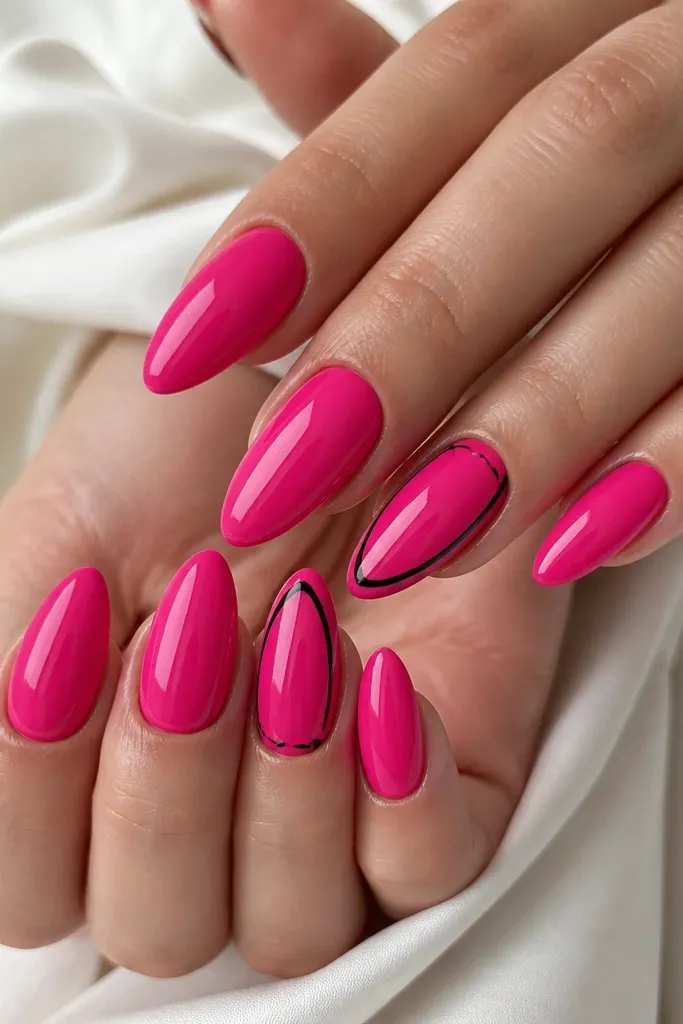 Hot pink almond nails with two accent nails outlined in thin black glossy lines. The outline traces part of the nail shape near the sides and tip, with crisp separation and high shine.