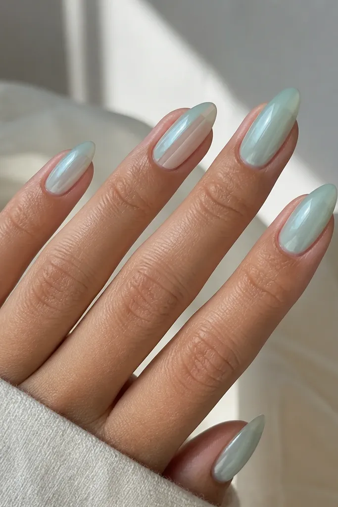 Medium-length almond nails painted in a translucent sea-glass mint. One nail accent shows a clean negative-space stripe running down one side from near the cuticle to the tip. The rest of the nails have a soft, frosty shine like glass with a glassy top coat.