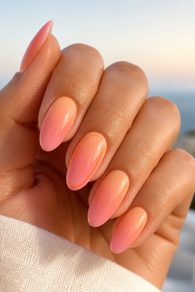 Medium almond nails with a smooth sunset gradient: peach at the cuticle fading into coral and then pale pink at the tip. One accent nail has a thin orange outline following the nail shape near the sides. Everything is glossy and bright like summer light.