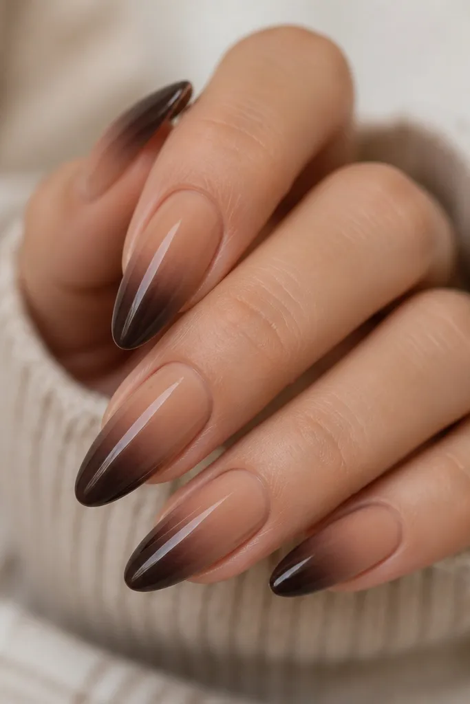 Almond nails with a smooth ombré starting in a warm toffee nude near the cuticle and fading into a deep chocolate brown at the tips. The transition is soft and blended, with no harsh line. The nails are glossy and the gradient follows the nail's natural curvature.