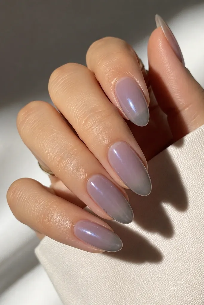 Almond nails with a lavender smoke base that looks semi-translucent and hazy. The tips fade into a translucent grey, with a smooth gradient and slightly smoky edge. The nails are glossy and the fade looks like it's wrapped in fog.