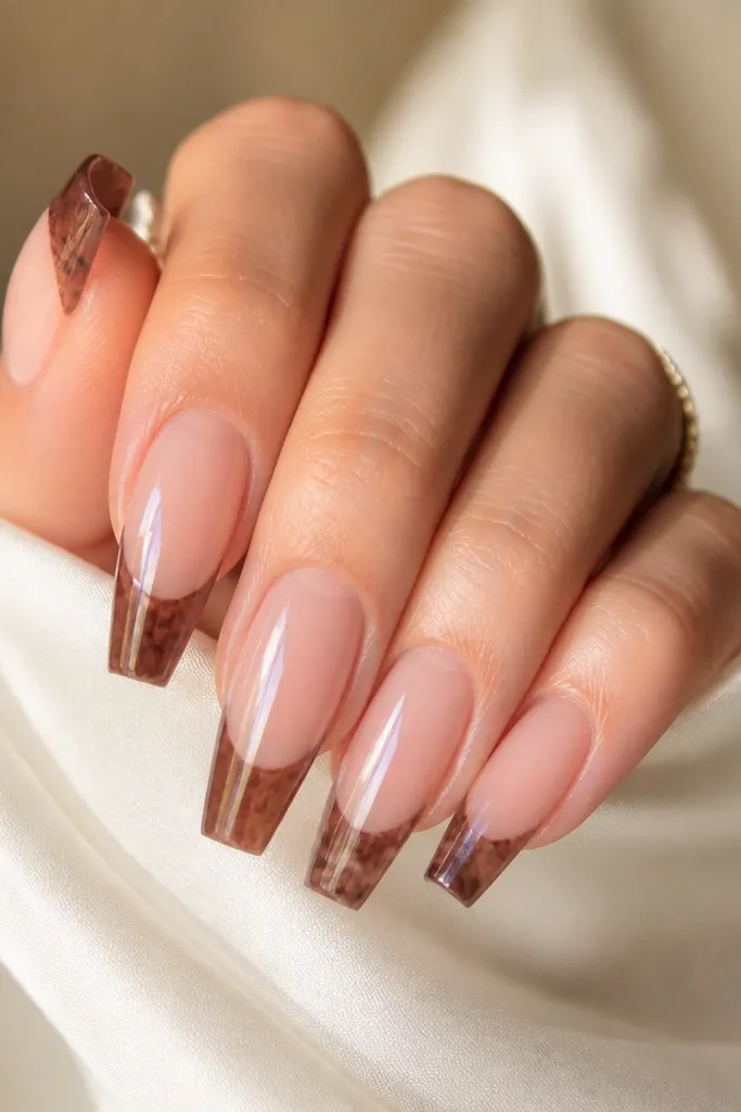 Medium-length coffin nails with a clear BIAB shine. Only the tips have chocolate-brown marbling: thin, cloudy streaks and veins on a semi-sheer brown wash. The rest of the nail is see-through and glossy, with a natural cuticle zone.