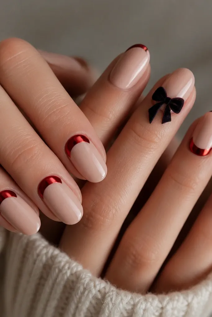 Two accent nails show a black velvet bow on a deep nude base. The velvet bow has a soft, fuzzy texture effect with a tiny highlight edge. The other nails have a glossy red chrome half-moon at the cuticle with a sheer nude rest of nail. Everything is sharp and symmetrical, with a clean cuticle line.