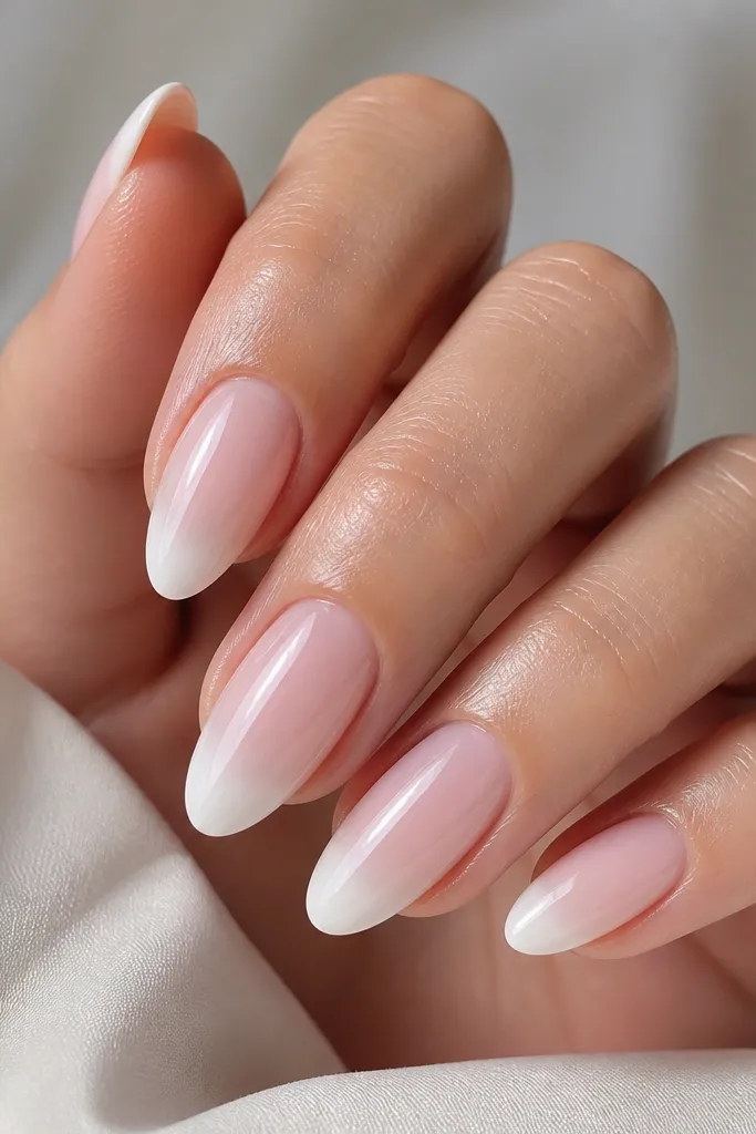Almond nails with a sheer pink BIAB base. The tips start as opaque white right at the edge and fade into the nude toward the middle of the free edge. Smooth gradient with high shine.