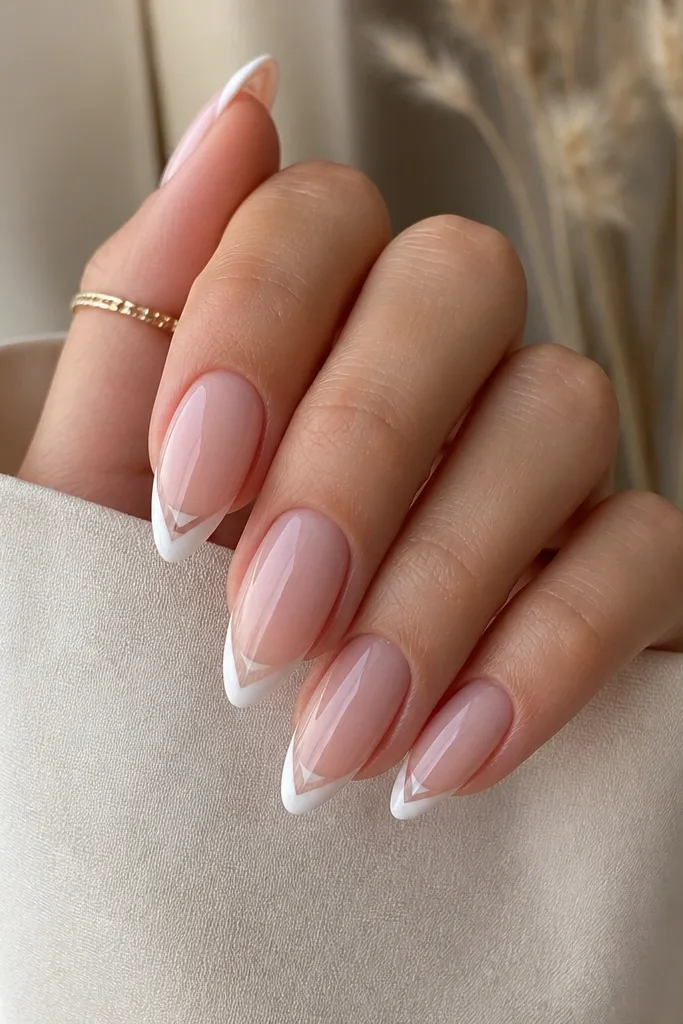 Almond nails with nude BIAB. The French tip is white but has a tiny clear triangle in the center at the top of the smile curve, creating a sharp negative space detail.