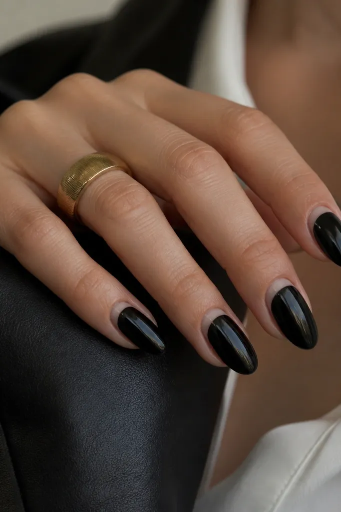 Deep black BIAB nails with a glossy finish. A reverse French line runs near the cuticle in a sheer nude band, giving a clean crescent near the base. The rest of the nail stays black.