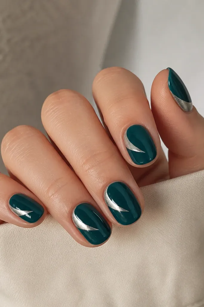 Short oval nails in glossy deep teal. On each nail there's a silver chrome half-swoosh that curves from the outer side toward the center, like a crescent. Clean edges, high shine chrome.