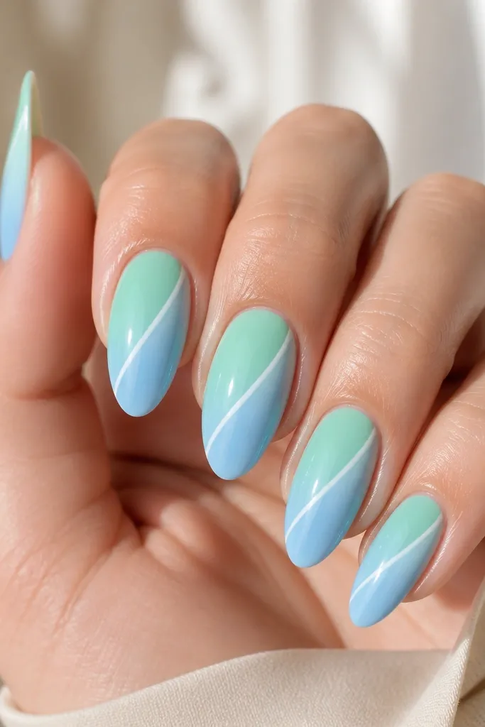 Five medium-length almond nails. Each nail has a smooth ombre from mint green at the cuticle fading into a soft sky blue at the tip. A crisp white stripe sits diagonally from the lower center to near the upper sidewall, like a sunbeam. The nails are glossy and clean, with no extra rhinestones.