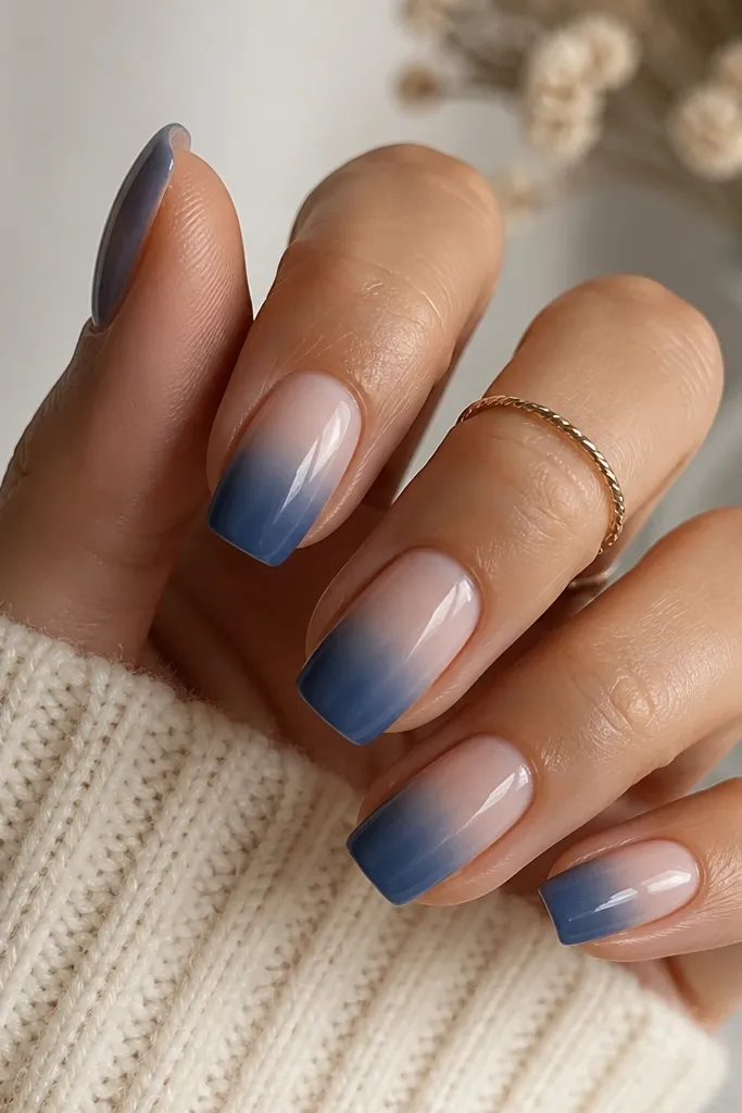 Squoval nails with a nude base fading into a dusty denim blue ombré; the deepest denim sits near the free edge, fading softly toward the cuticle.