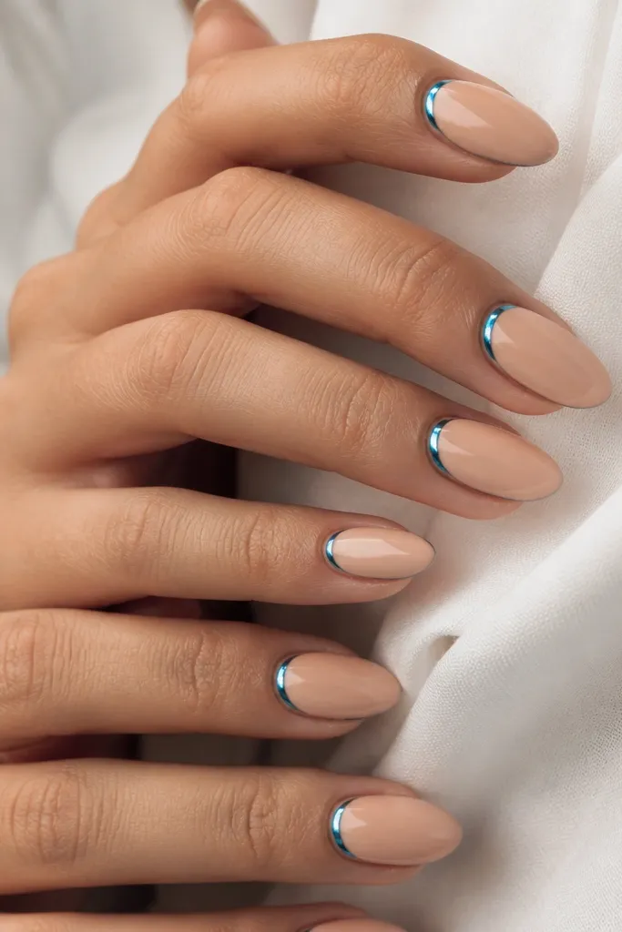 Almond nails with a nude base and a thin crescent of blue chrome just around the cuticle area; the rest of the nail is glossy nude.