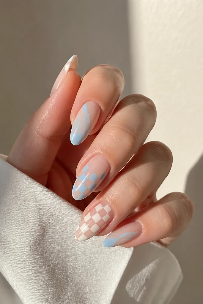 Almond nails with a nude base and alternating blue and white checker pattern on two nails; the other nails have a solid icy blue accent stripe.