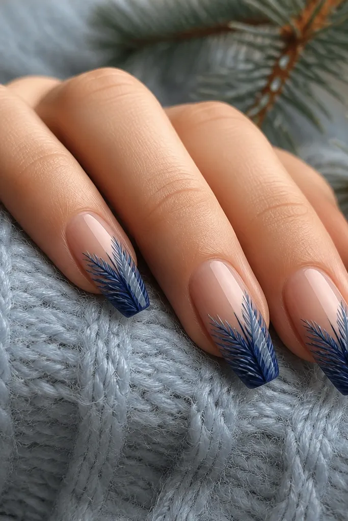 Medium coffin nails with a nude base and deep blue tips painted like pine needles; thin light-blue highlights pick out the needle strokes.