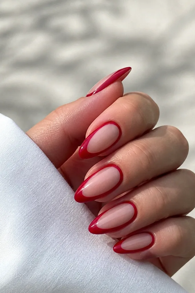 Almond nails with a cherry red border arc around a clear negative-space window in the center; glossy topcoat.