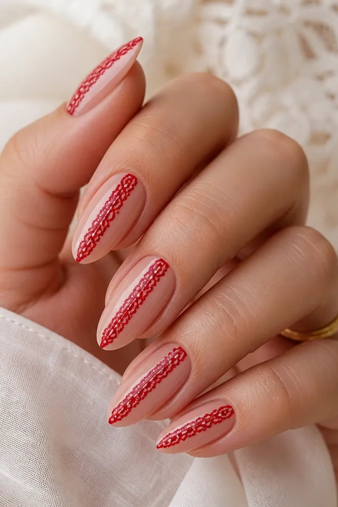 Almond nails with a nude base. A vertical lace stripe runs down the center in glossy red, with tiny white dots and thin lines like lace thread.
