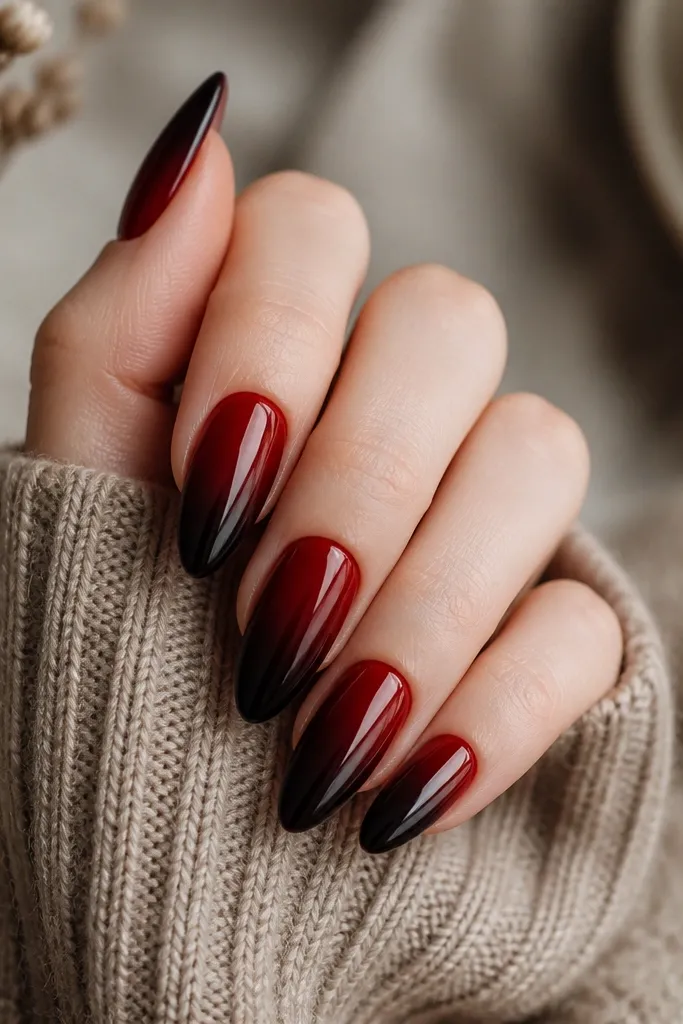 Almond nails with a smooth gradient from a dark red near the cuticle into a nearly black, deep burgundy at the tips. The ombre is blended with no harsh line and a glossy finish.