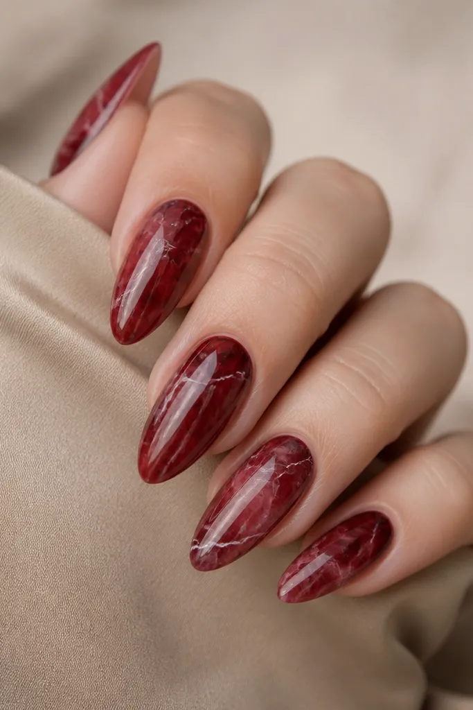 Almond nails with dark red marbling and thin, delicate white veins. The pattern looks like smoky marble with a glossy finish and veins that branch naturally.