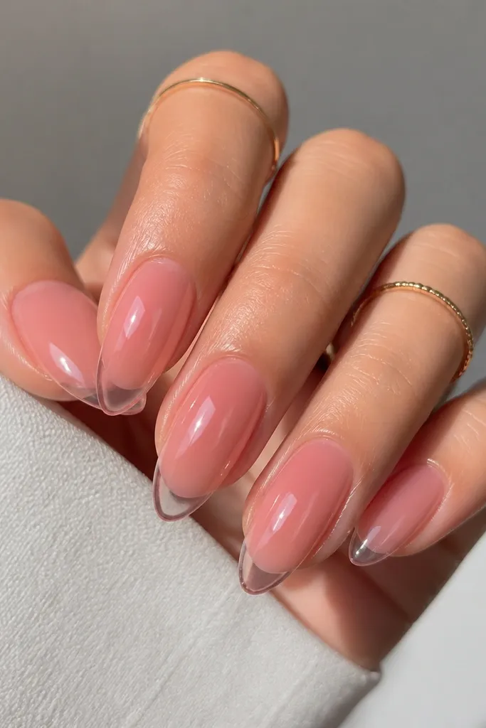 Almond nails in a translucent pink jelly. The center looks rosy and see-through, with a subtle clear or sheer halo near the tip, giving a floating effect under the glossy top coat.